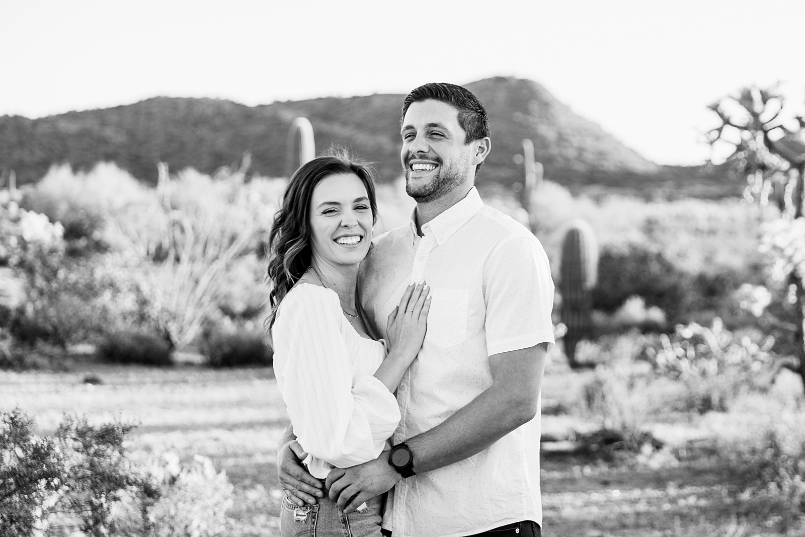 Couple laugh together during their desert engagement session by Phoenix engagement photographer PMA Photography.