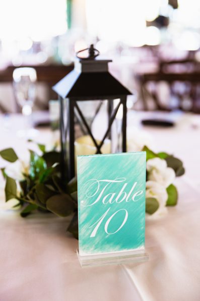 Lantern wedding centerpieces with teal table numbers by PMA Photography.
