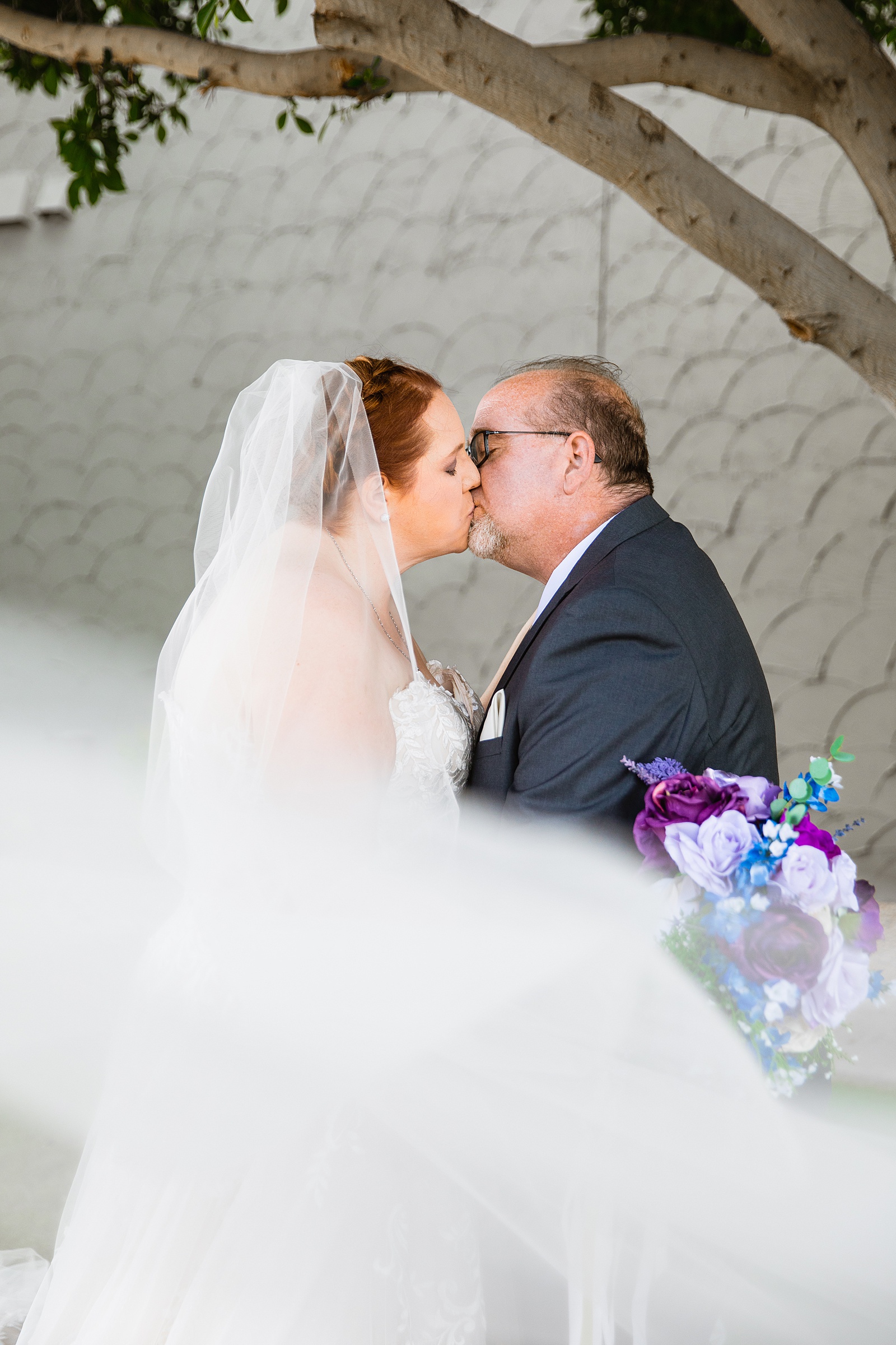 Bride and groom share a kiss during their Sun Valley Church wedding by Arizona wedding photographer PMA Photography.