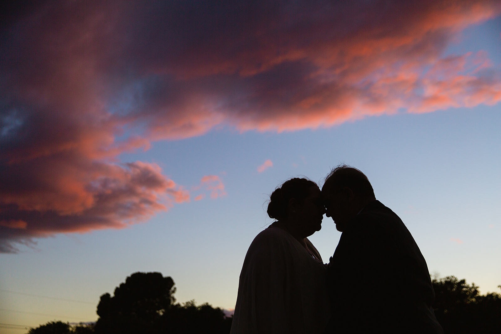 Silhouette of bride and groom at sunset by PMA Photography.