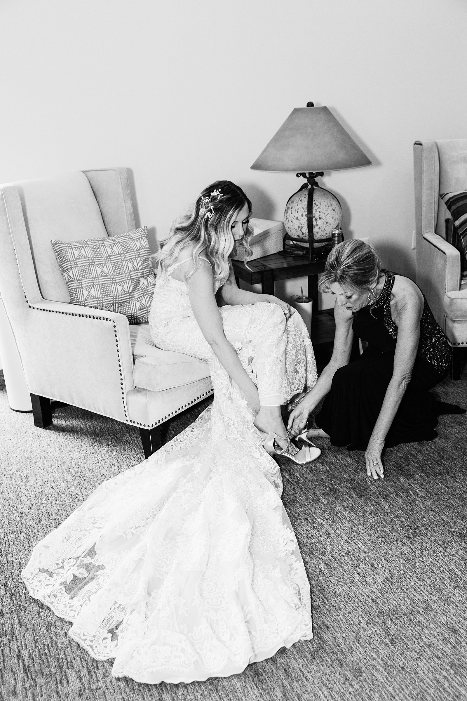 Bride's mother helping her put her shoes on at Brides romantic, lace wedding dress at her desert wedding at Troon North by Scottsdale wedding photographer PMA Photography.