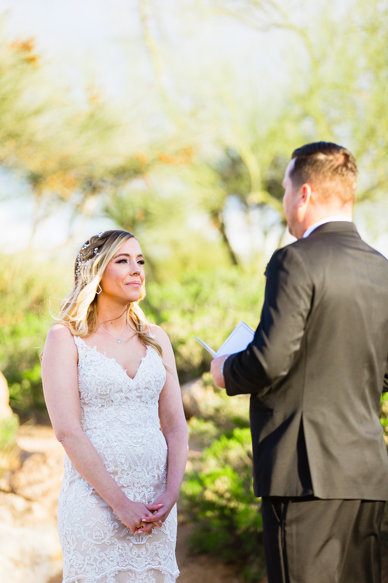 Bride and groom exchange vows during their Troon North wedding ceremony by Scottsdale wedding photographer PMA Photography.