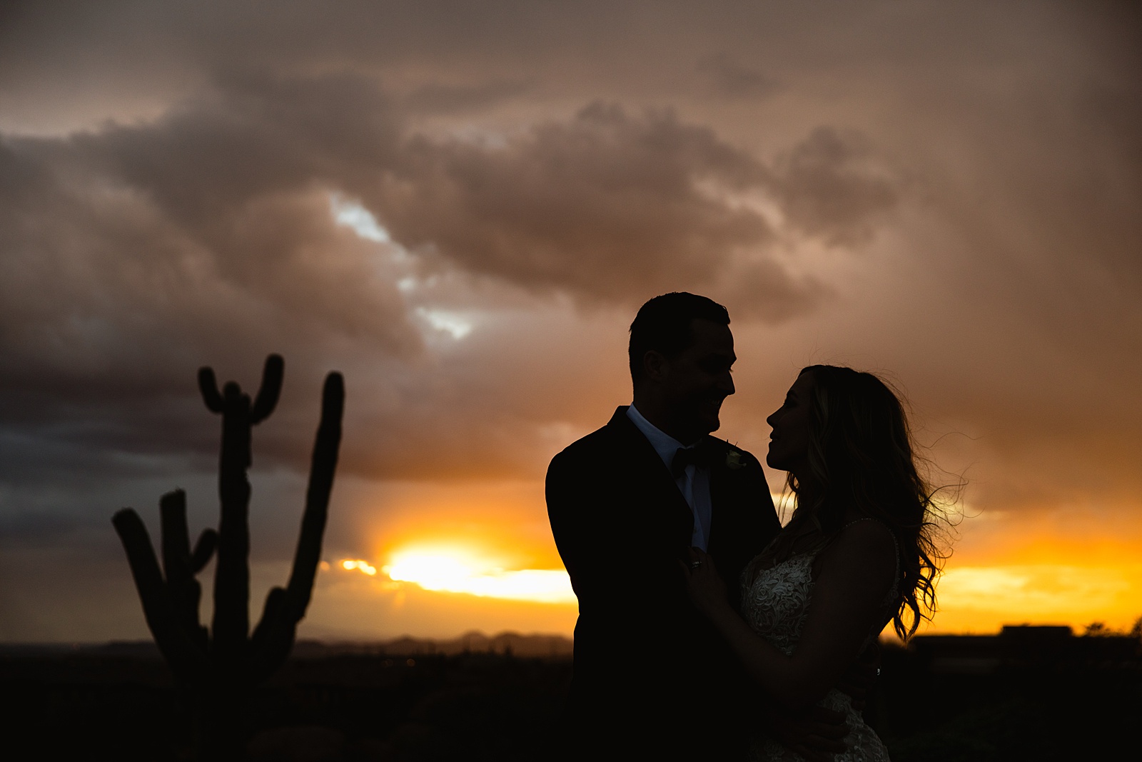 Silhouette of a bride and groom at sunset in the desert at their Troon North wedding by Scottsdale wedding photographer PMA Photography.