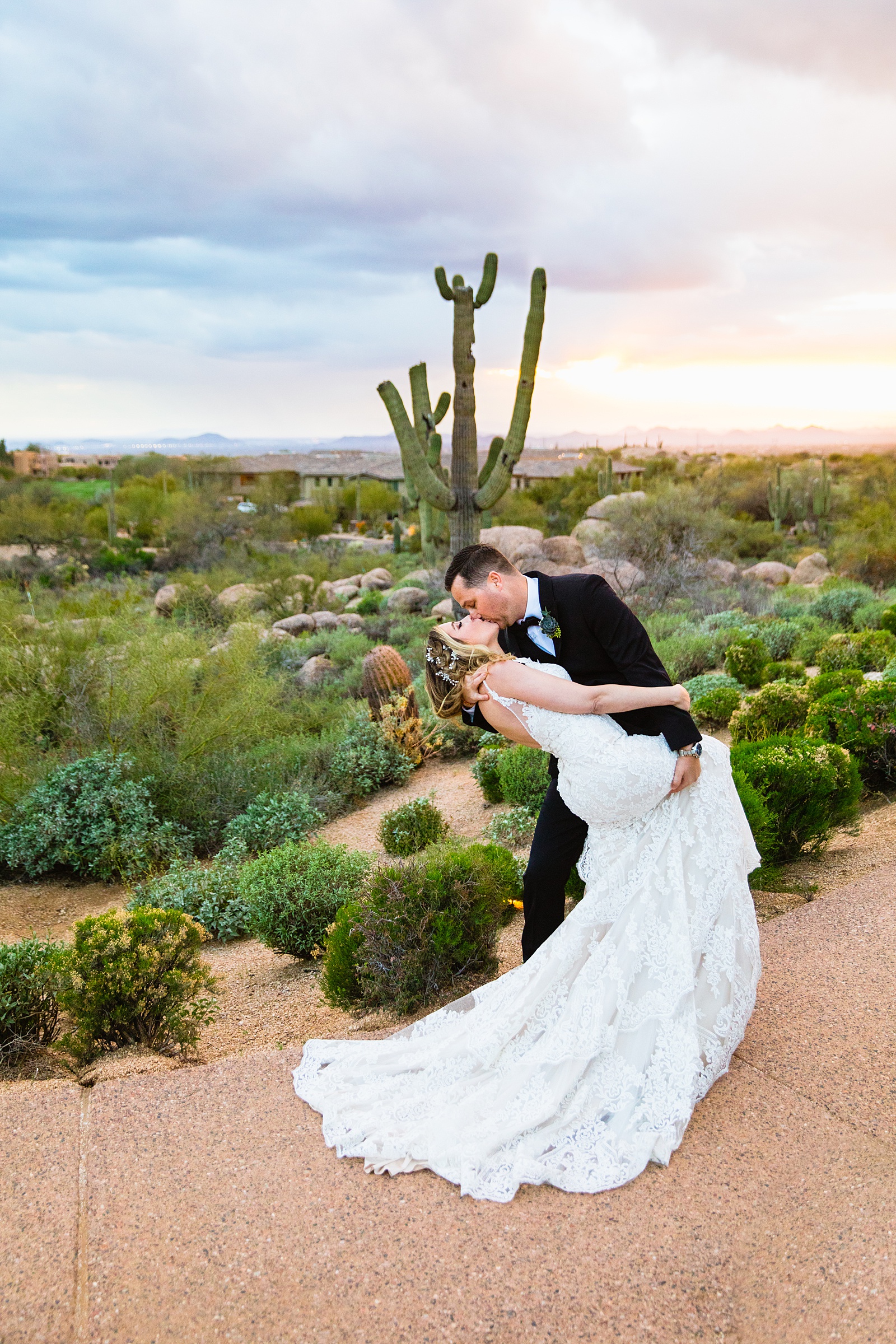 Groom dipping the bride in the desert at sunset at their Troon North wedding by Scottsdale wedding photographer PMA Photography.