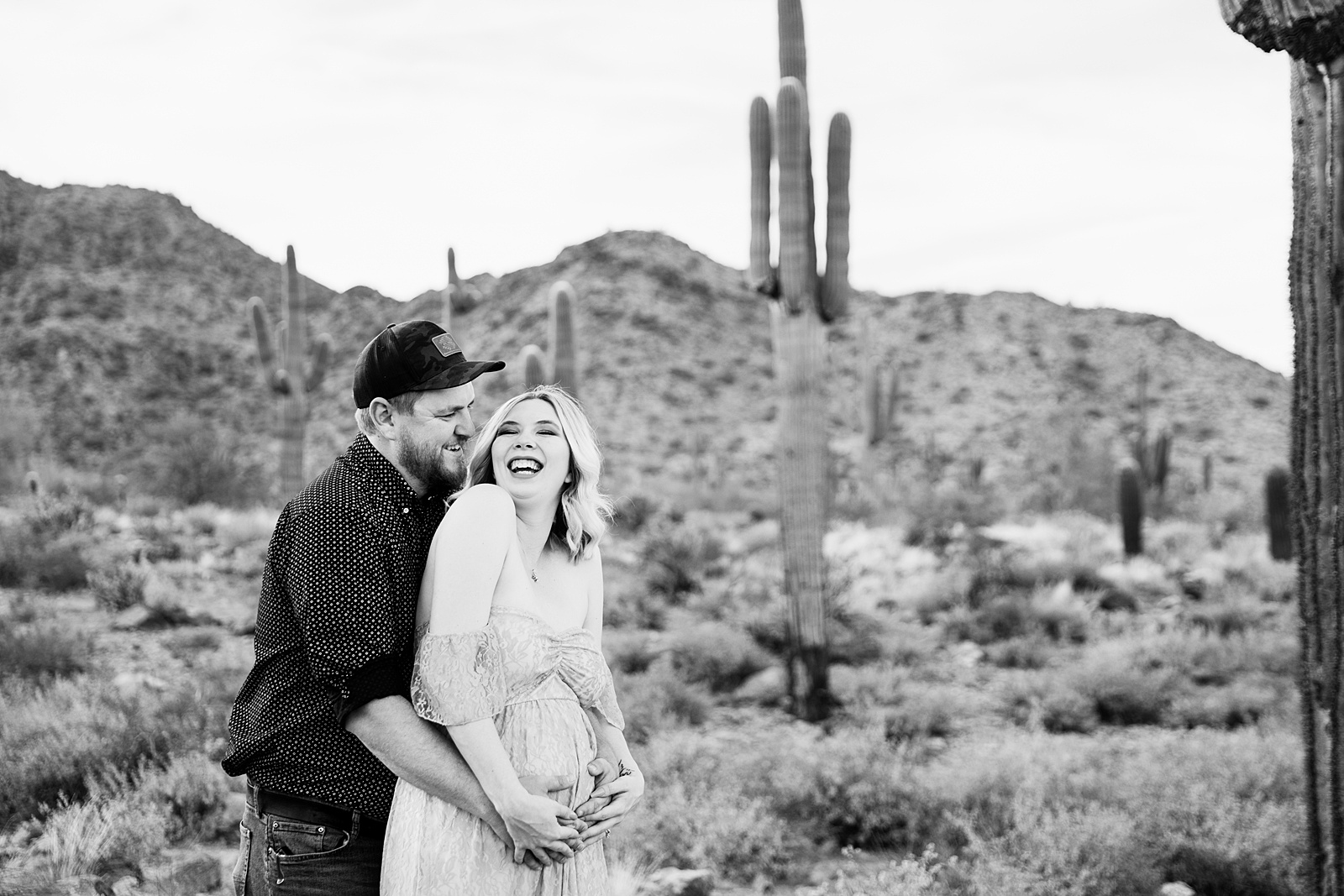 Couple laugh together during their Phoenix maternity session by Arizona maternity photographer PMA Photography.