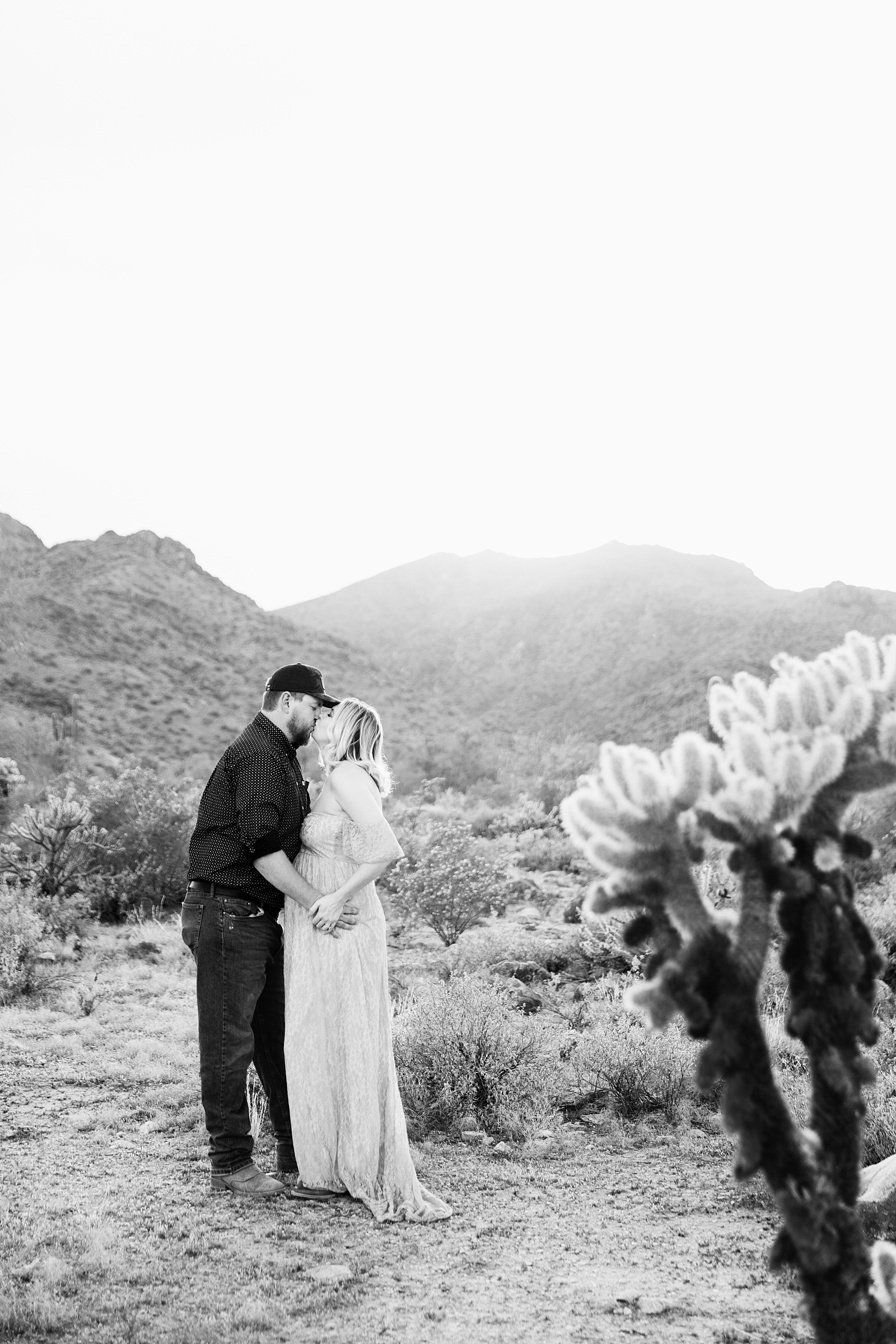 Couple share a kiss during their White Tanks Desert maternity session by Phoenix maternity photographer PMA Photography.