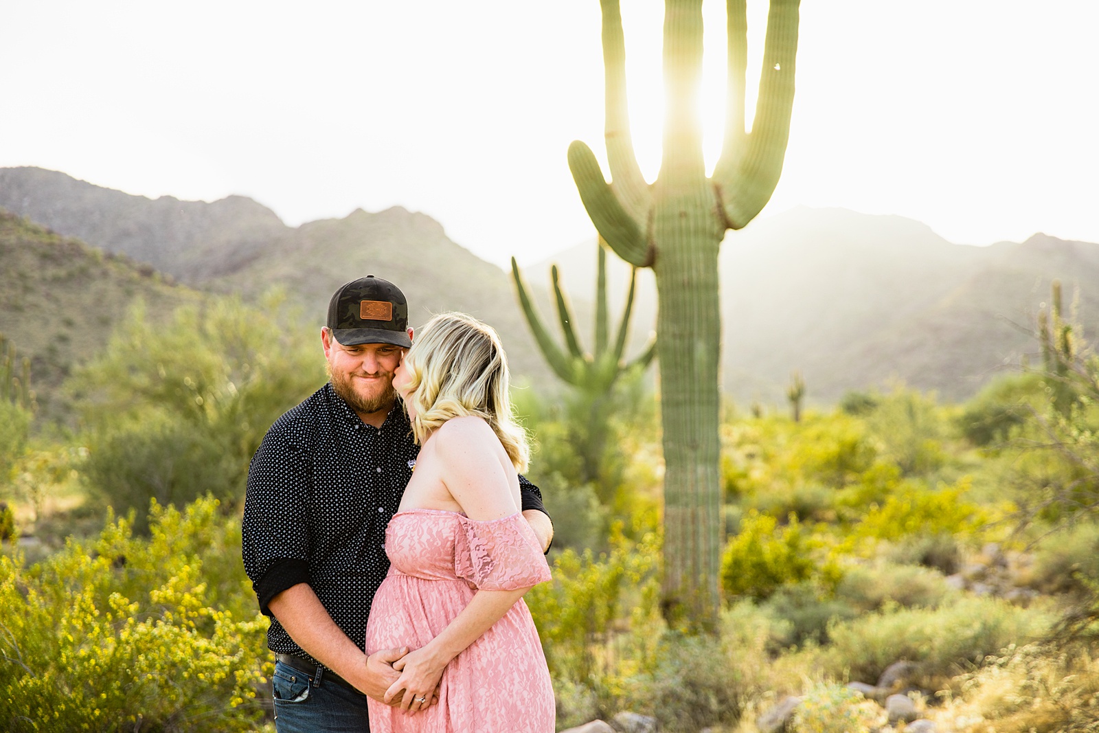 Couple share a kiss during their White Tanks Desert maternity session by Phoenix maternity photographer PMA Photography.