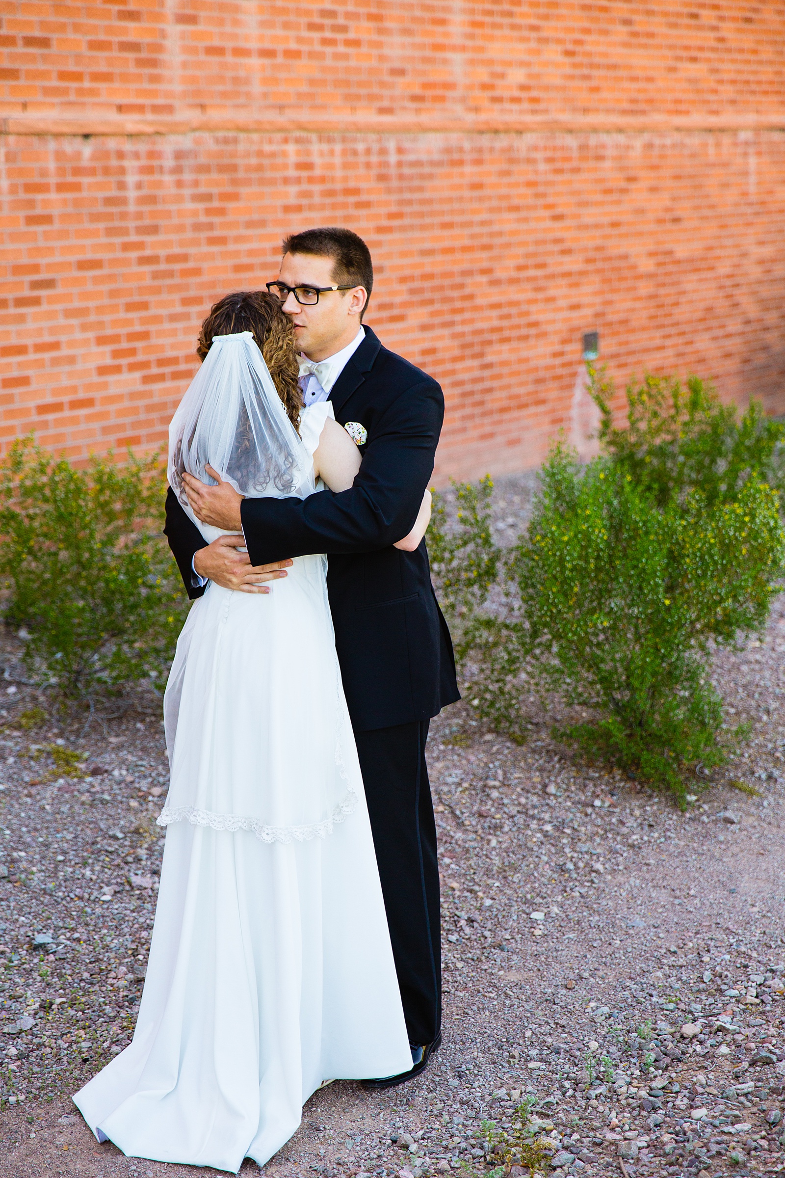 Bride and groom share an intimate moment during their first look at Arizona Historical Society by Tempe wedding photographer PMA Photography.
