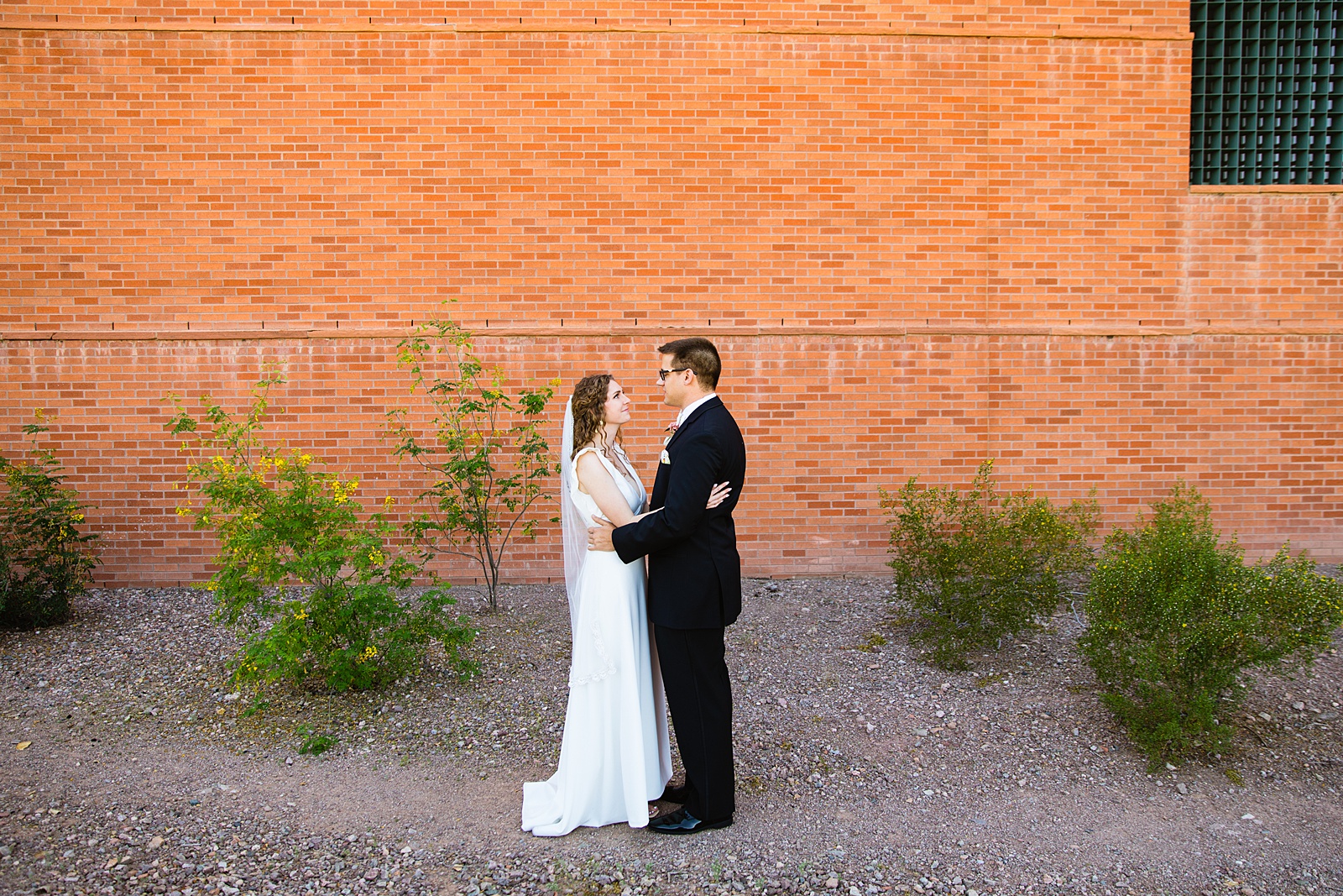 Bride and groom share an intimate moment during their first look at Arizona Historical Society by Phoenix wedding photographer PMA Photography.