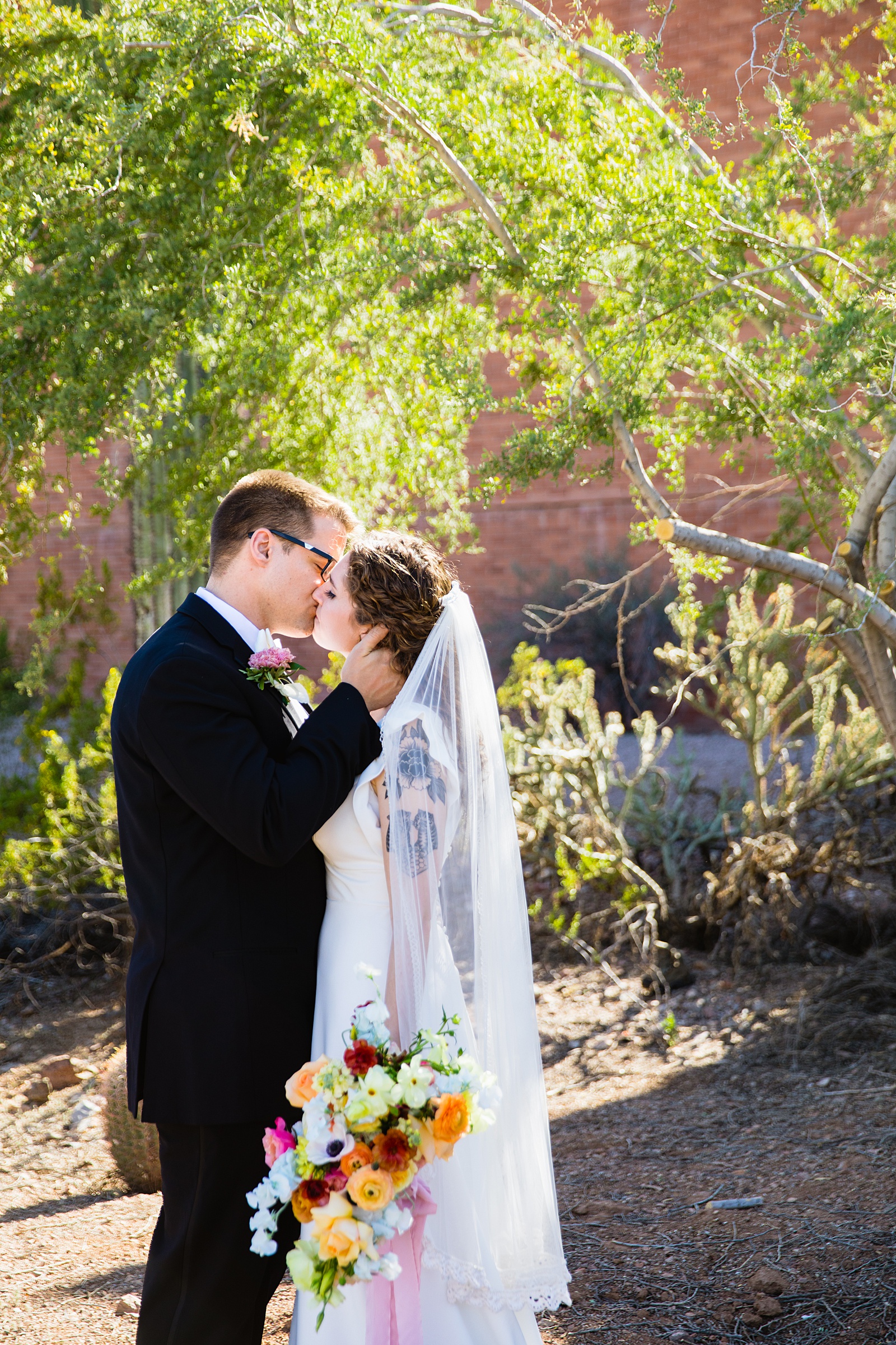 Bride and groom share a kiss during their Arizona Historical Society wedding by Tempe wedding photographer PMA Photography.