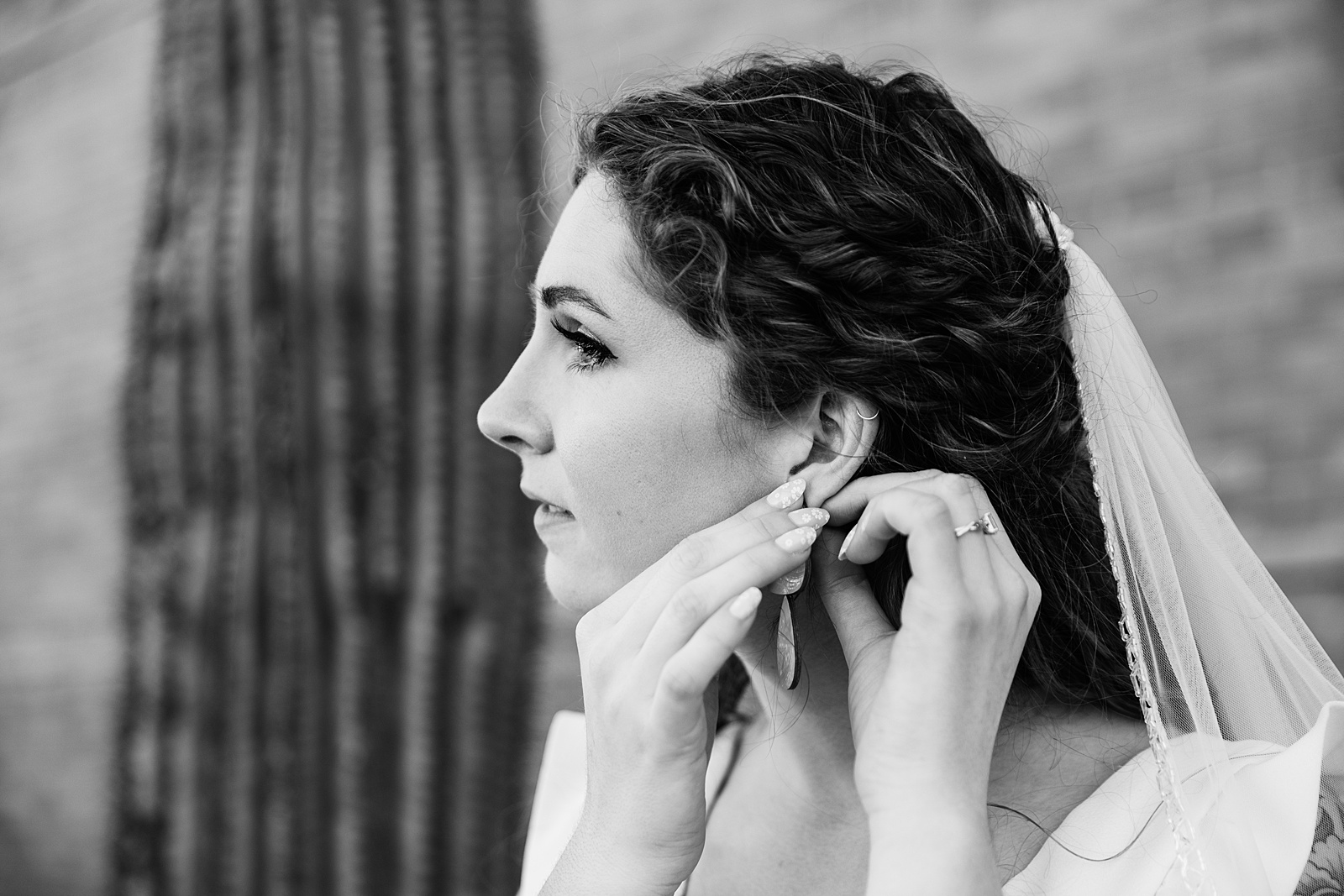 Bride adjusting her earrings on her wedding day by Tempe wedding photographers PMA Photography.