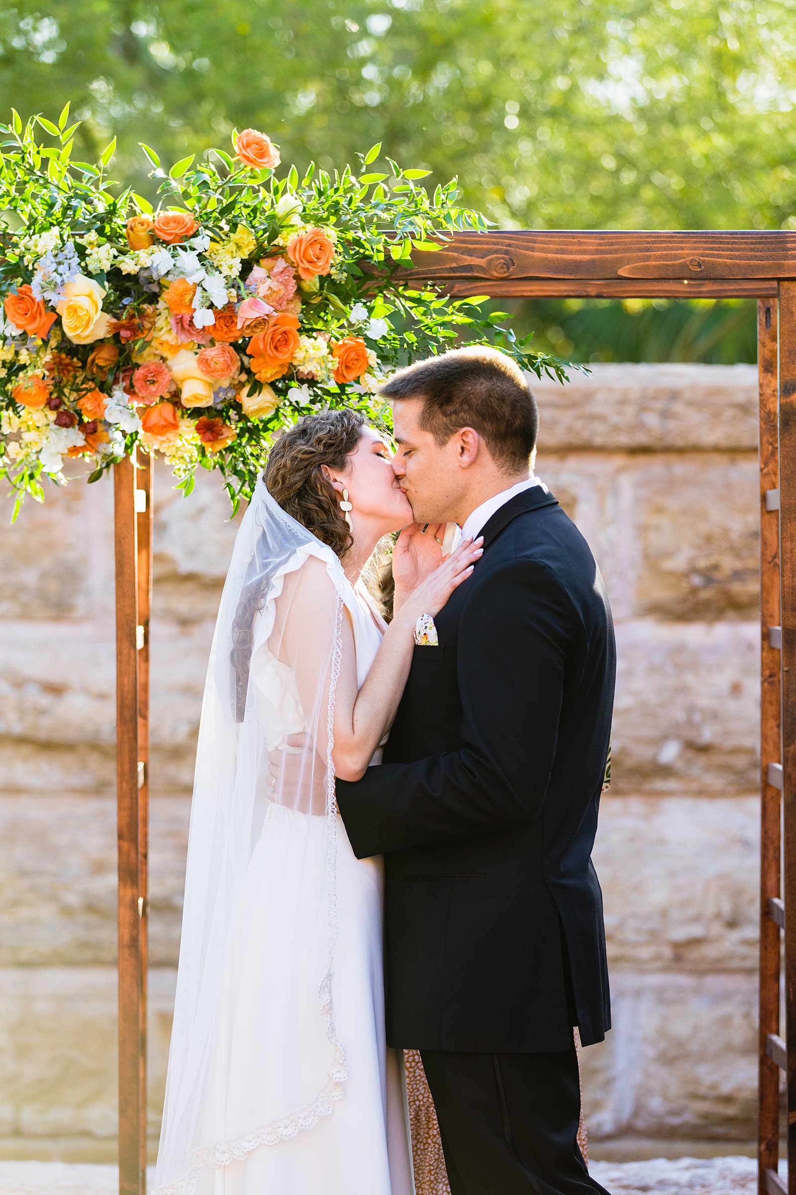 Bride and groom share their first kiss during their wedding ceremony at Arizona Historical Society by Arizona wedding photographer PMA Photography.