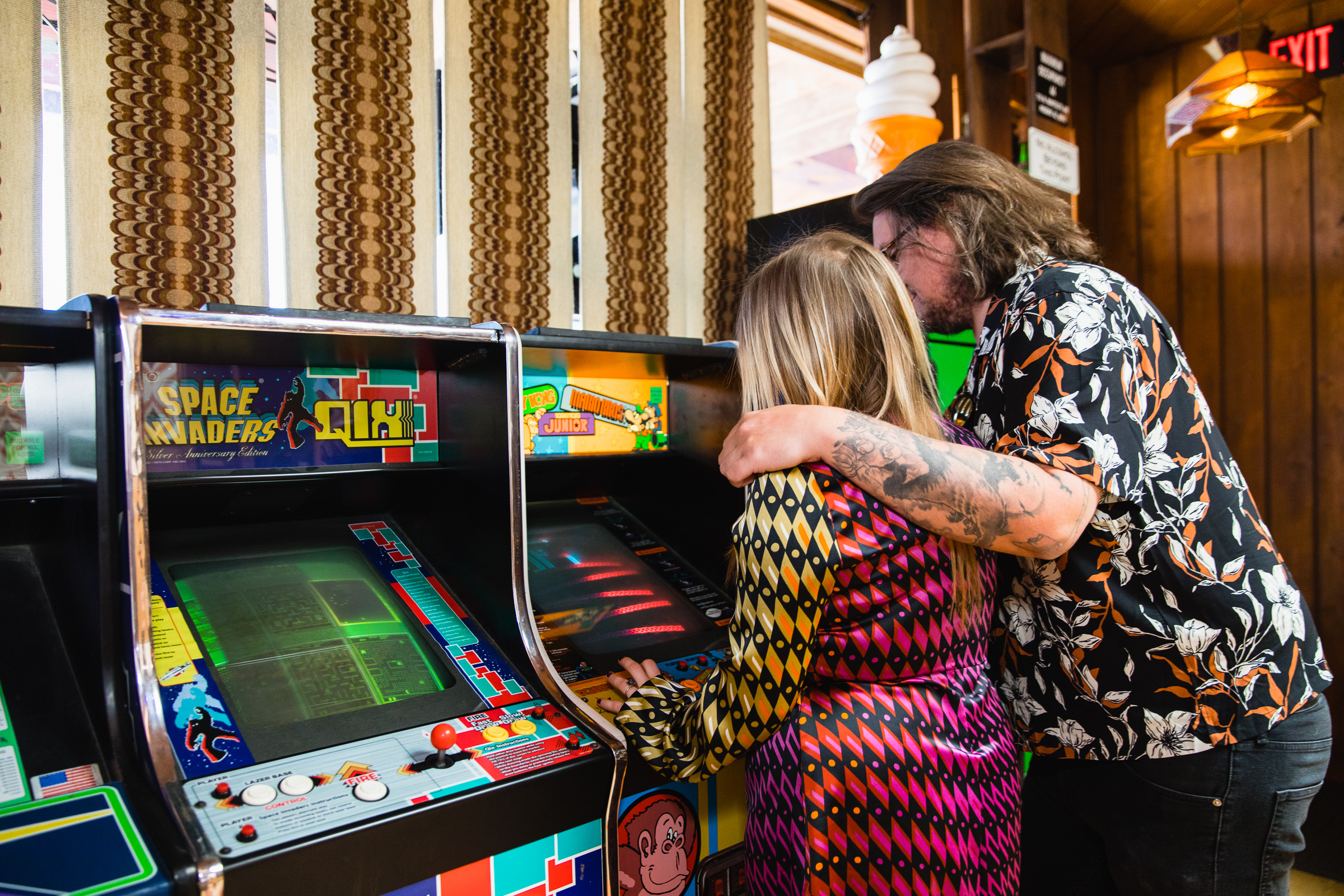 Couple playing arcade games together during their fun and unique Thunderbird Lounge engagement session by Phoenix wedding photographer PMA Photography.