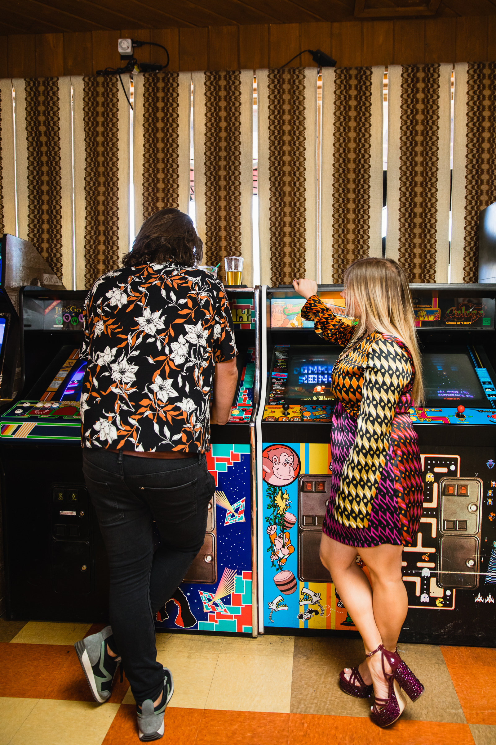 Couple playing arcade games together during their fun and unique Thunderbird Lounge engagement session by Phoenix wedding photographer PMA Photography.