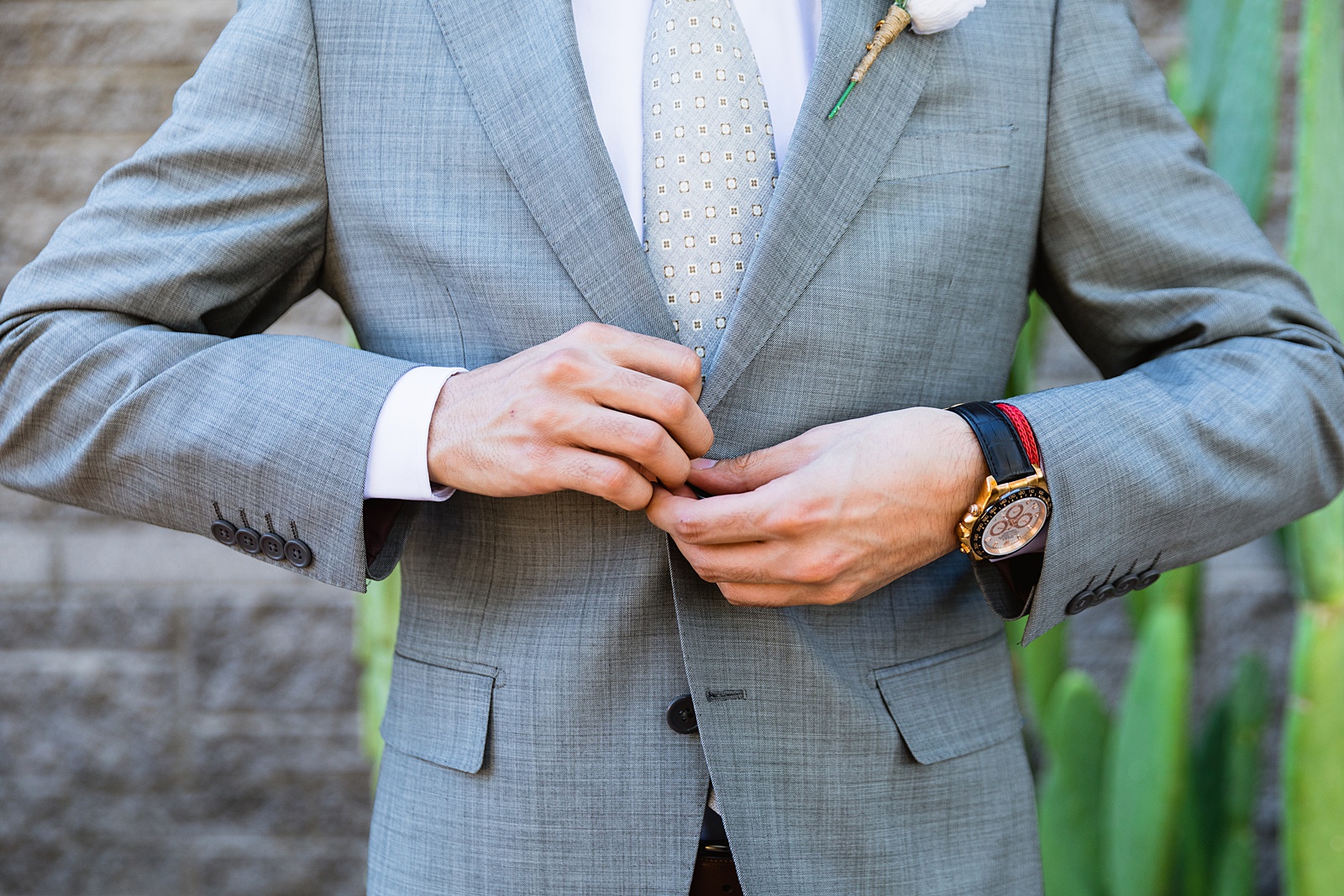 Groom buttoning his suit jacket for his wedding day by Scottdsale wedding photographers PMA Photography.