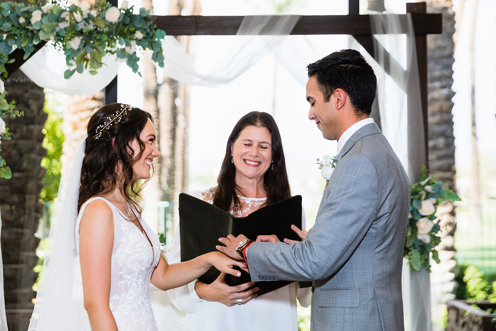 Bride and groom exchange rings during their wedding ceremony at Hyatt Regency Scottsdale Resort & Spa At Gainey Ranch by Phoenix wedding photographer PMA Photography.