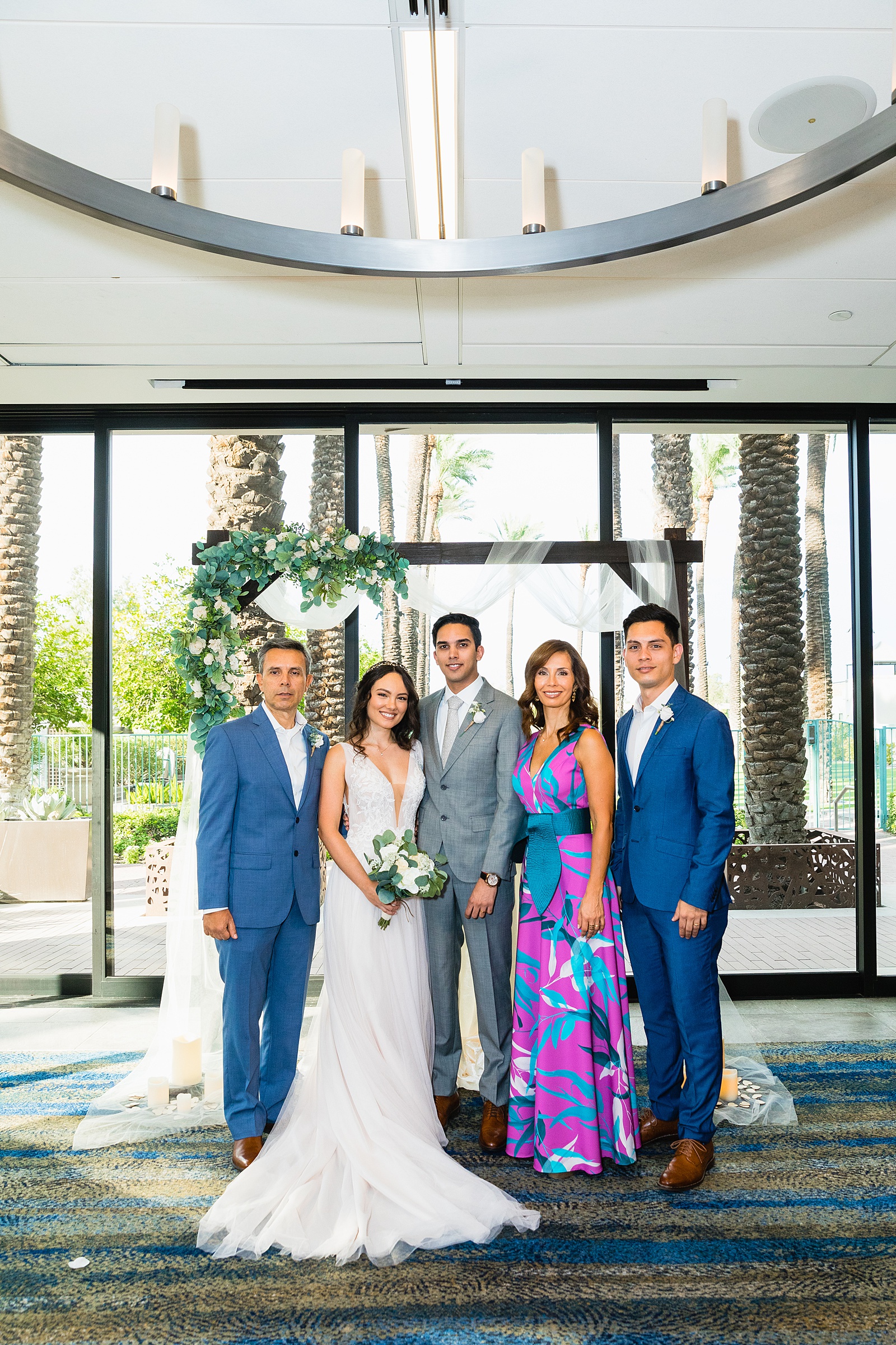 Bride and groom posing together with their family at a Hyatt Regency Scottsdale Resort & Spa At Gainey Ranch wedding by Arizona wedding photographer PMA Photography.