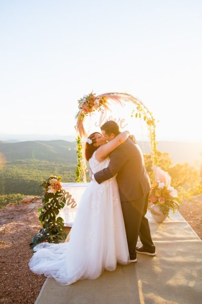 Adventurous couple share their first kiss during their wedding ceremony at Mogollon Rim by Arizona elopement photographer PMA Photography.