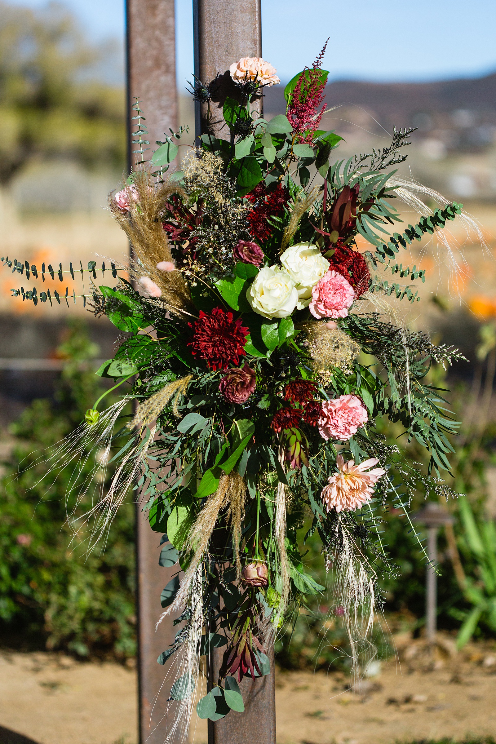 Flowers detail on ceremony arch at Mortimer Farms wedding reception by Prescott wedding photographer PMA Photography.