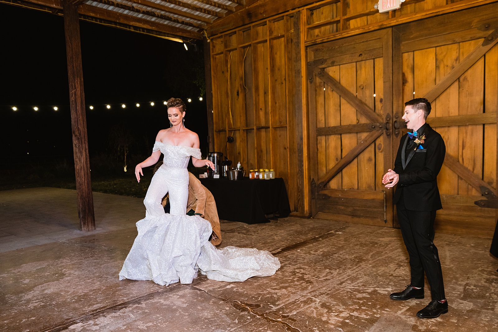 Bride changes out of wedding dress into wedding suit before dancing with guests at Mortimer Farms wedding reception by Prescott wedding photographer PMA Photography