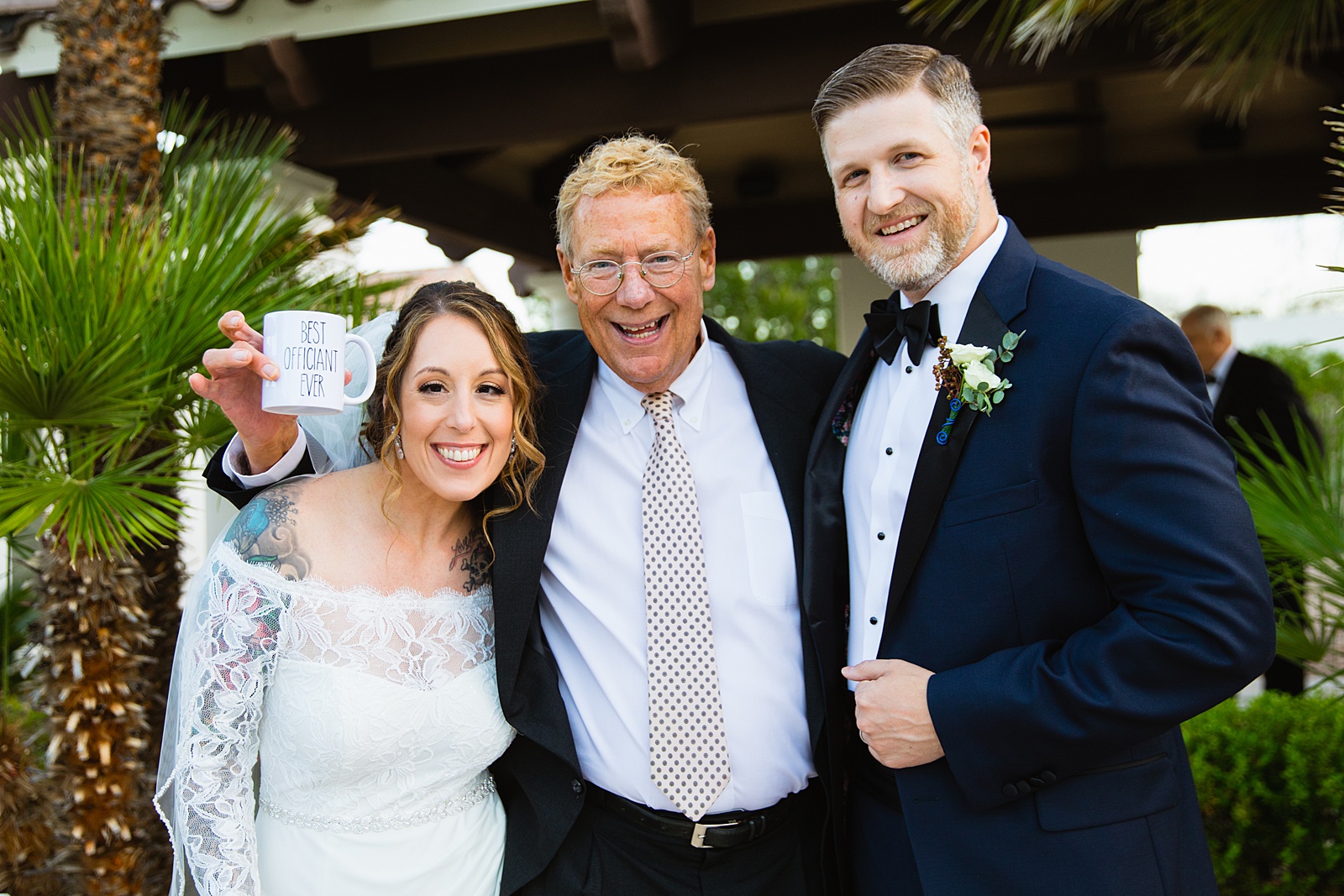 Newlyweds and their Officiant together at backyard wedding reception by Scottsdale wedding photographer PMA Photography