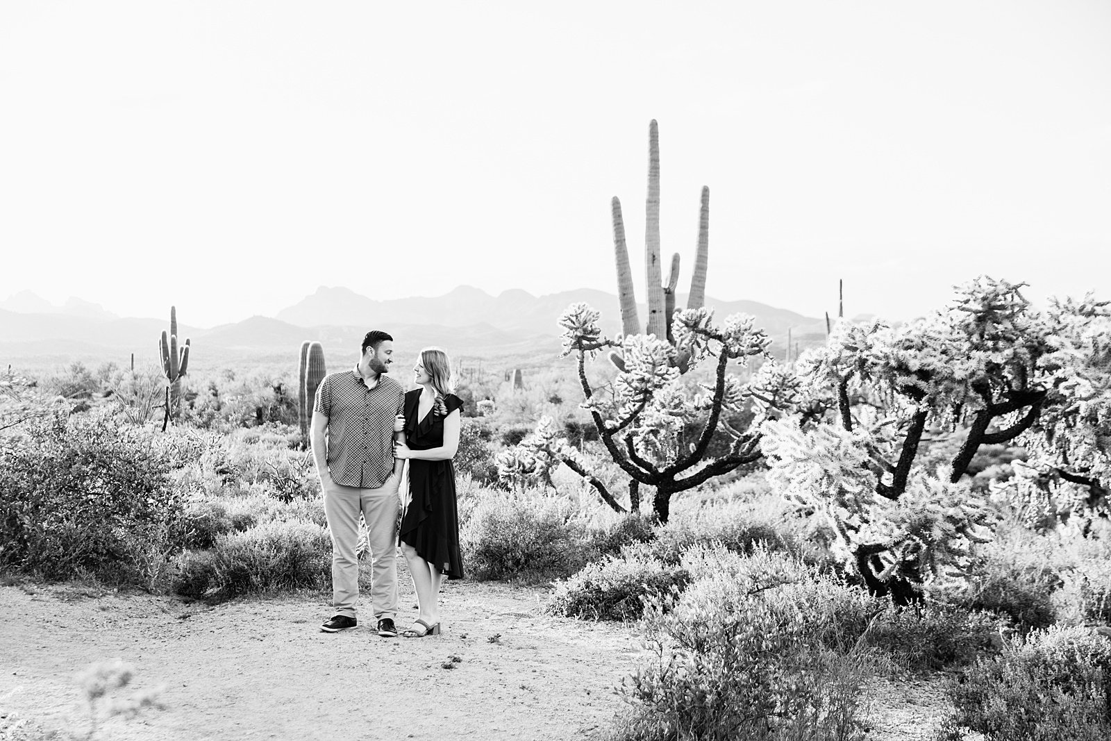 Couple look at each other during their Superstitions Mountain engagement session by Apache Junction wedding photographer PMA Photography.