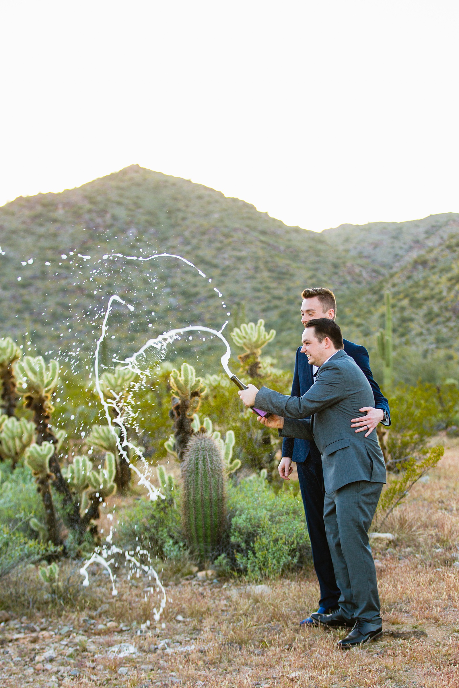 LGBTQ couple share a bottle of champange at their Phoenix elopement by Arizona elopement photographer PMA Photography.