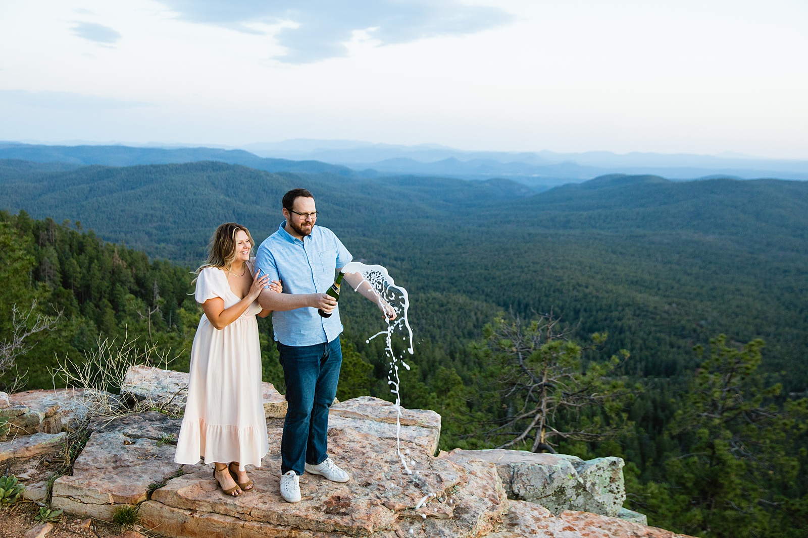 Couple popping champagne together during their Mogollon Rim engagement session by Payson engagement photographer PMA Photography.