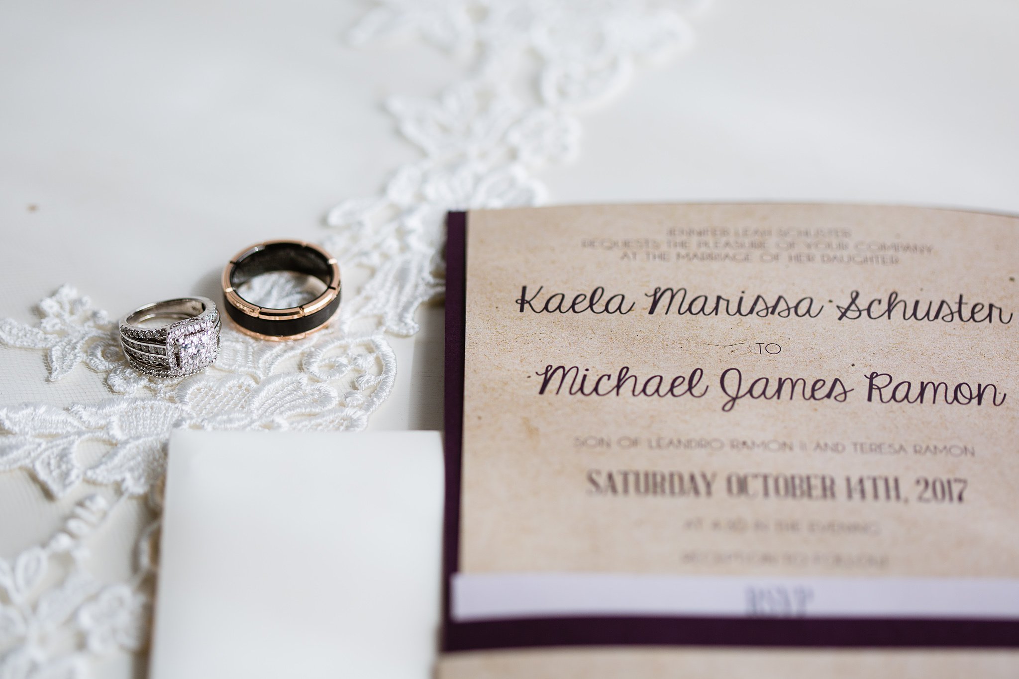 Image of rustic purple wedding invitations next to bride and groom's rings wedding details by Phoenix wedding photographer PMA Photography.