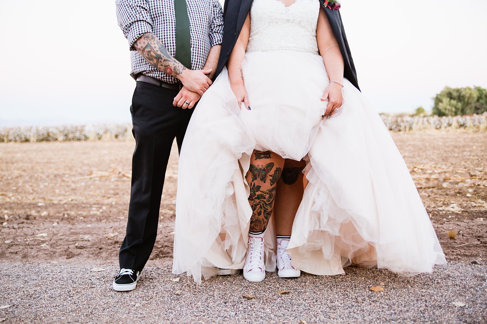 Bride and groom pose for a picture showing off their tattoos on their wedding day.