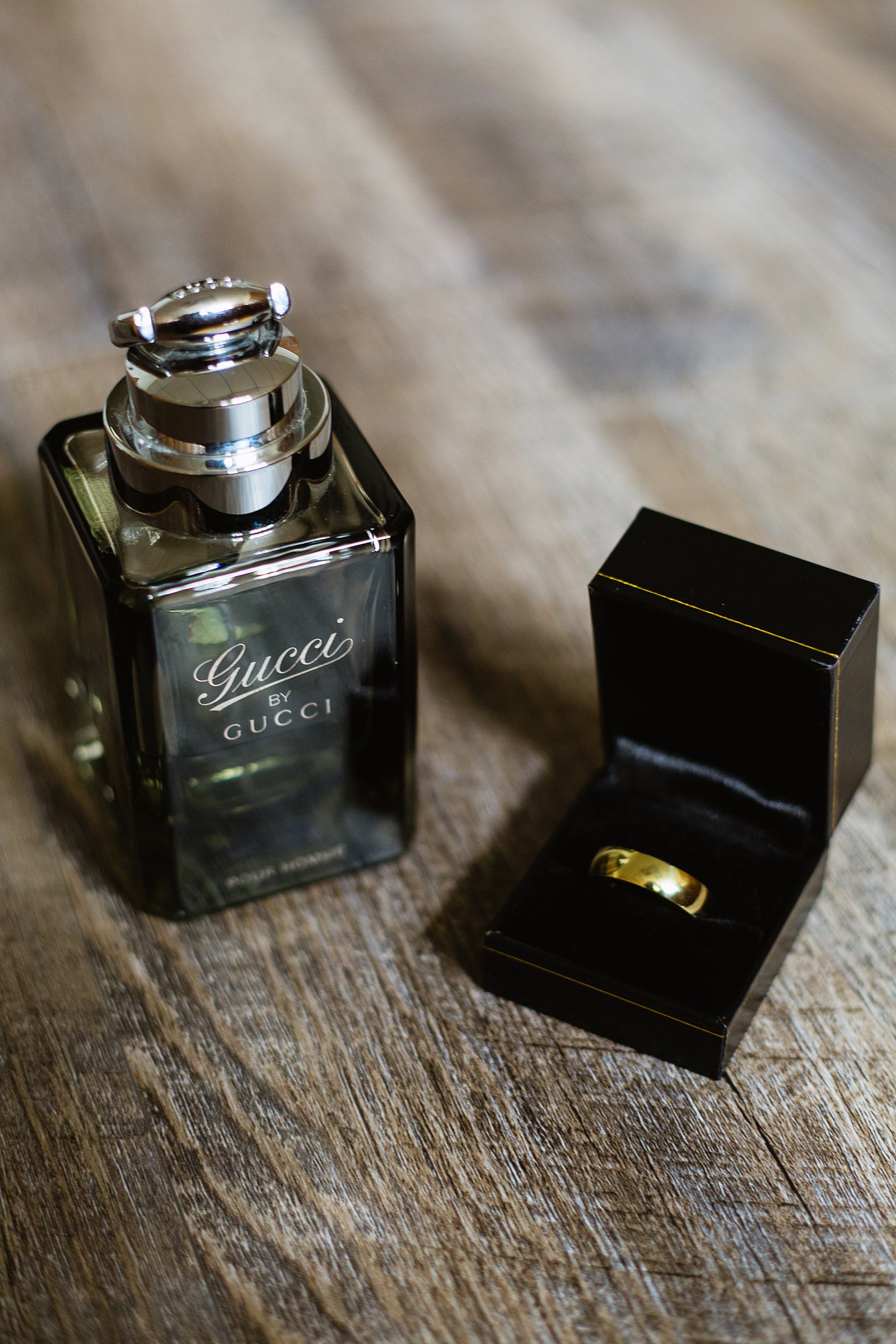 Groom's wedding day details of Gucci cologne and a simple gold wedding band by PMA Photography.