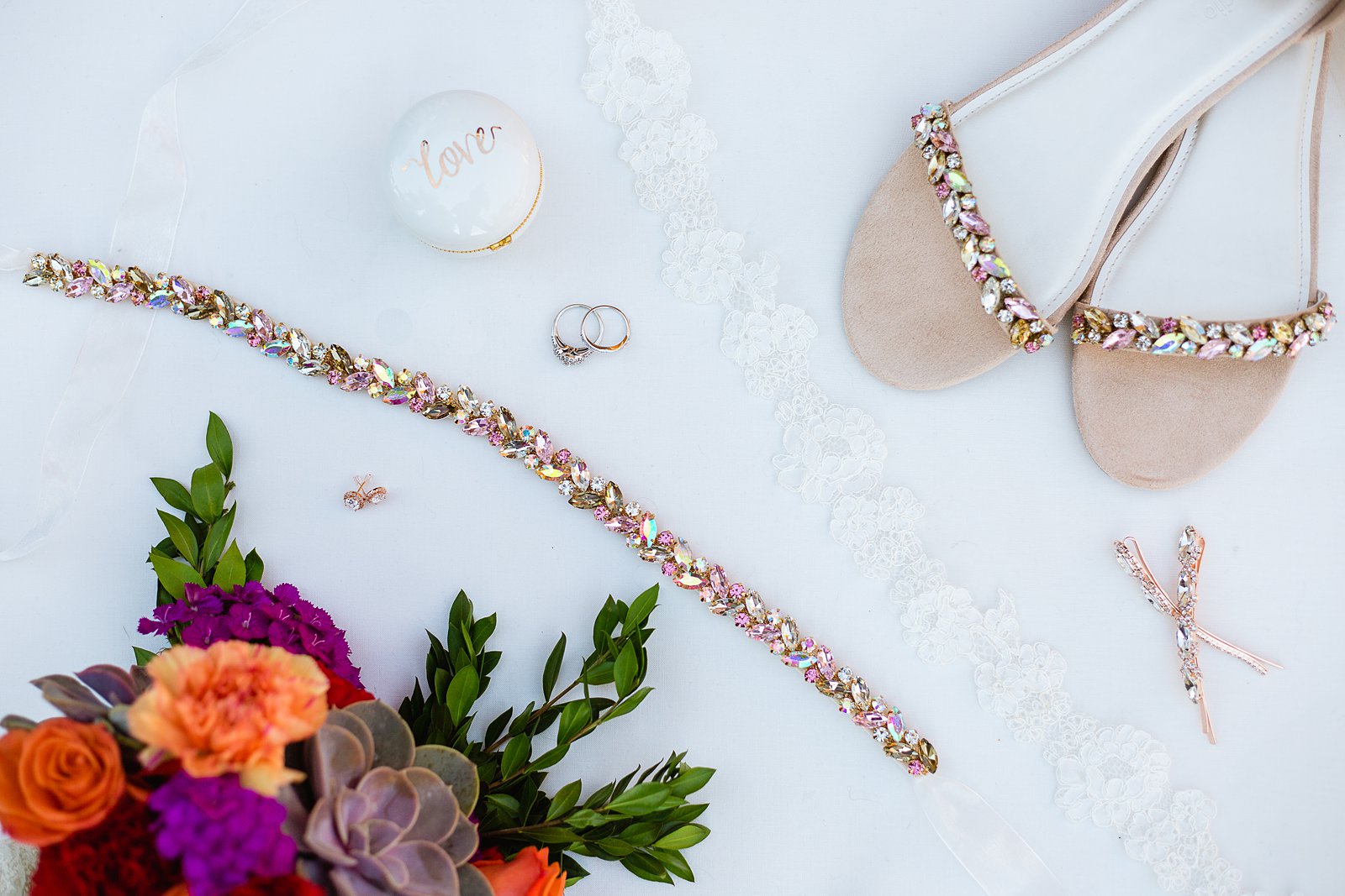 Bride's rose gold wedding details of shoes, rhinestone belt, hair clips, and earrings by PMA Photography.