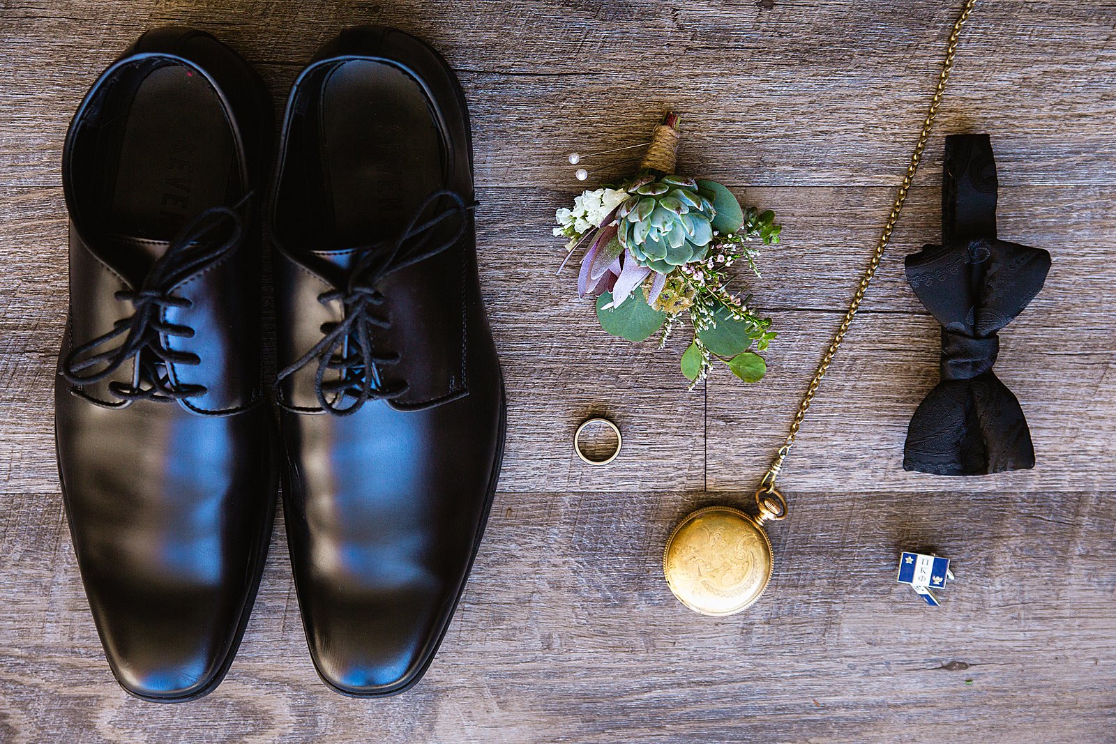 Groom's wedding day details of black bow tie, cuff links, succulent boutonniere, and pocket watch by PMA Photography.