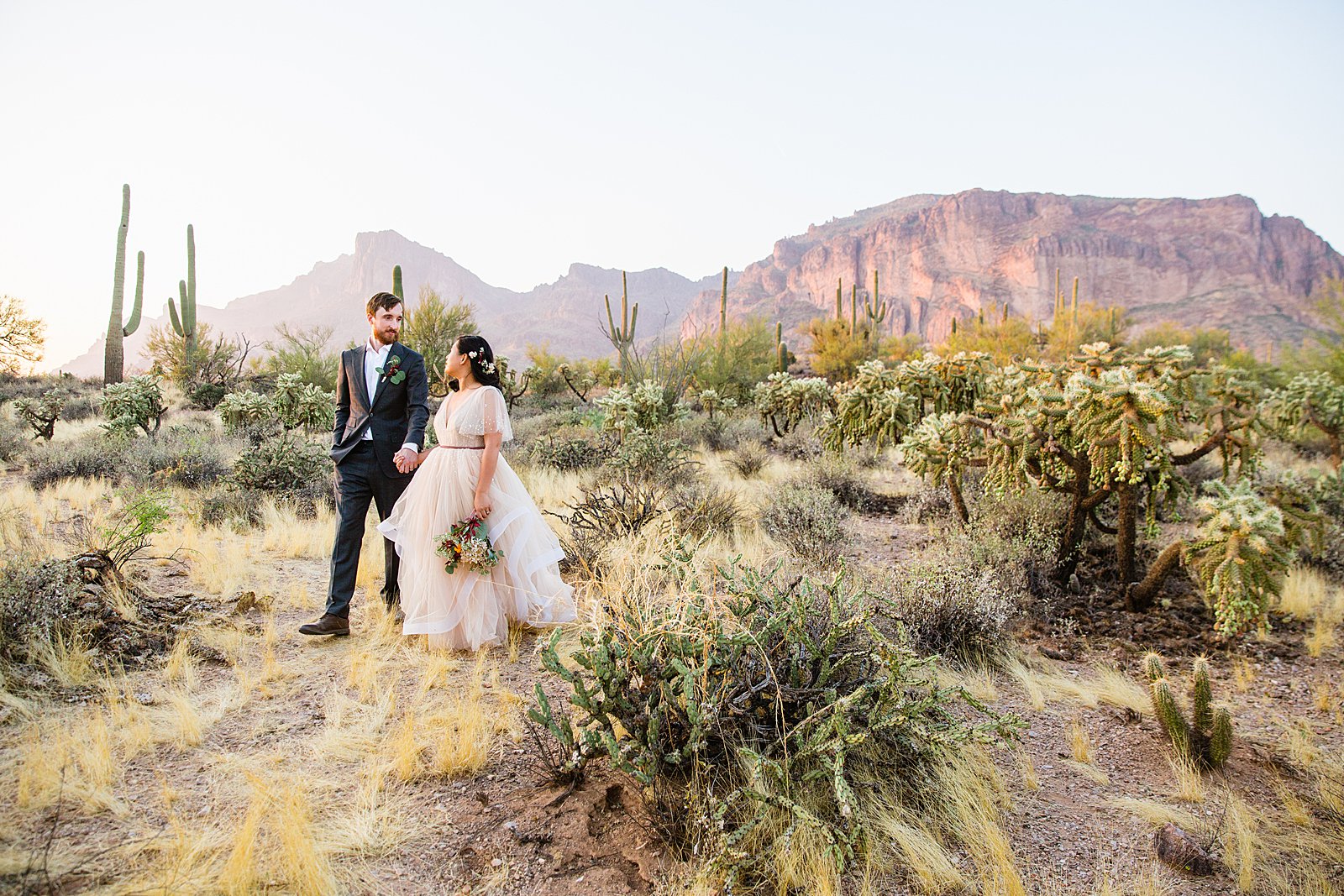 Bride and Groom walking together during their Superstition Mountain Cloth and Flame wedding by Arizona wedding photographer PMA Photography.