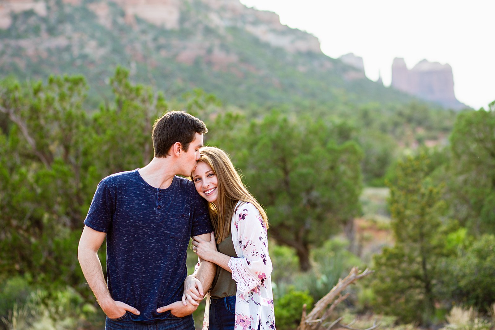 Couple share a kiss during their Bell Rock engagement session by Sedona wedding photographer PMA Photography.