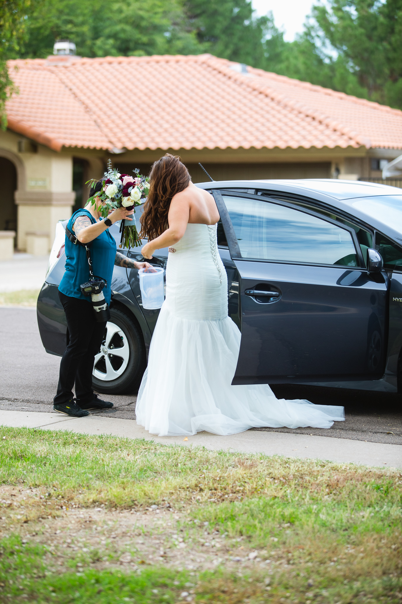 Amber of PMA Photography helping a bride out of a car.