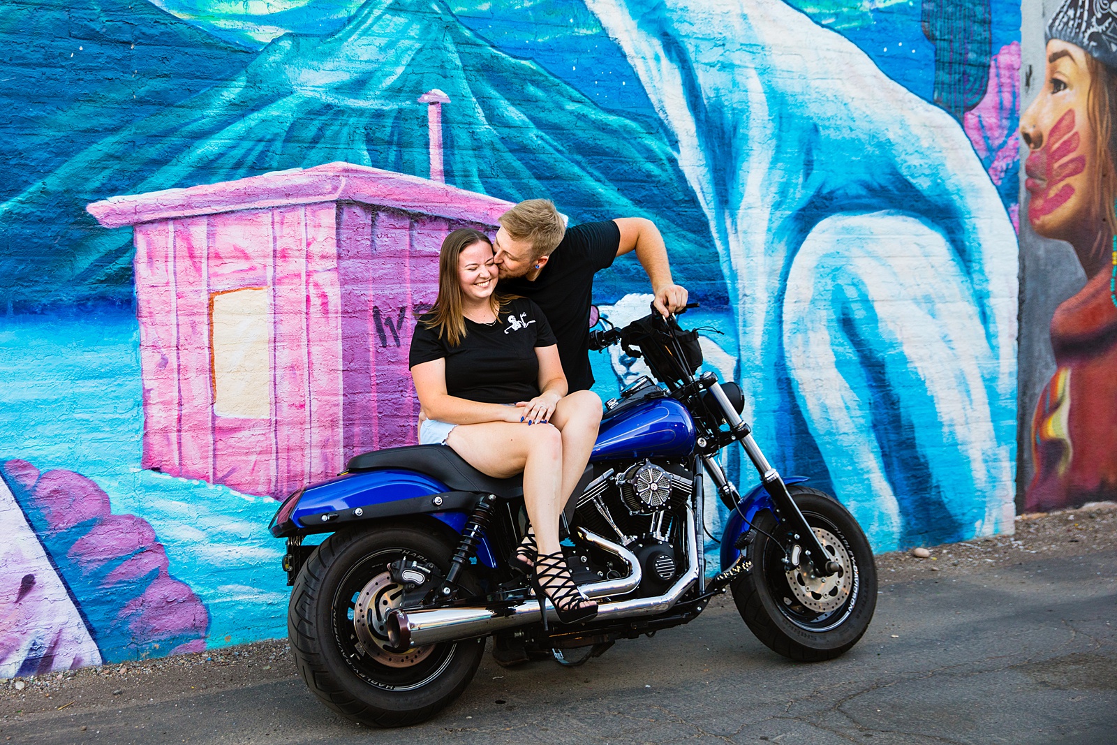 Adventurous couple share a kiss on a motorcycle during their Phoenix engagement session by Arizona wedding photographer PMA Photography.